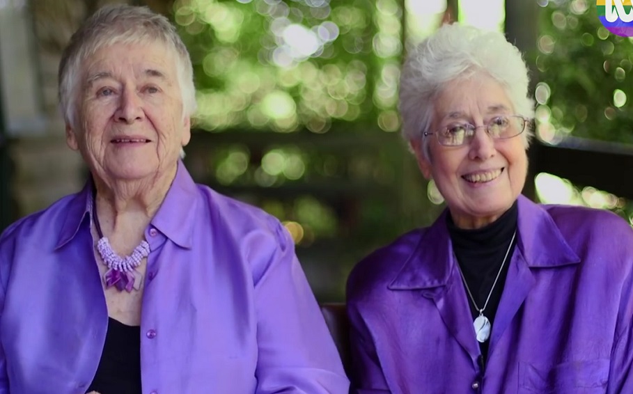 two older women both with gret\ying hair and wearing purple tops