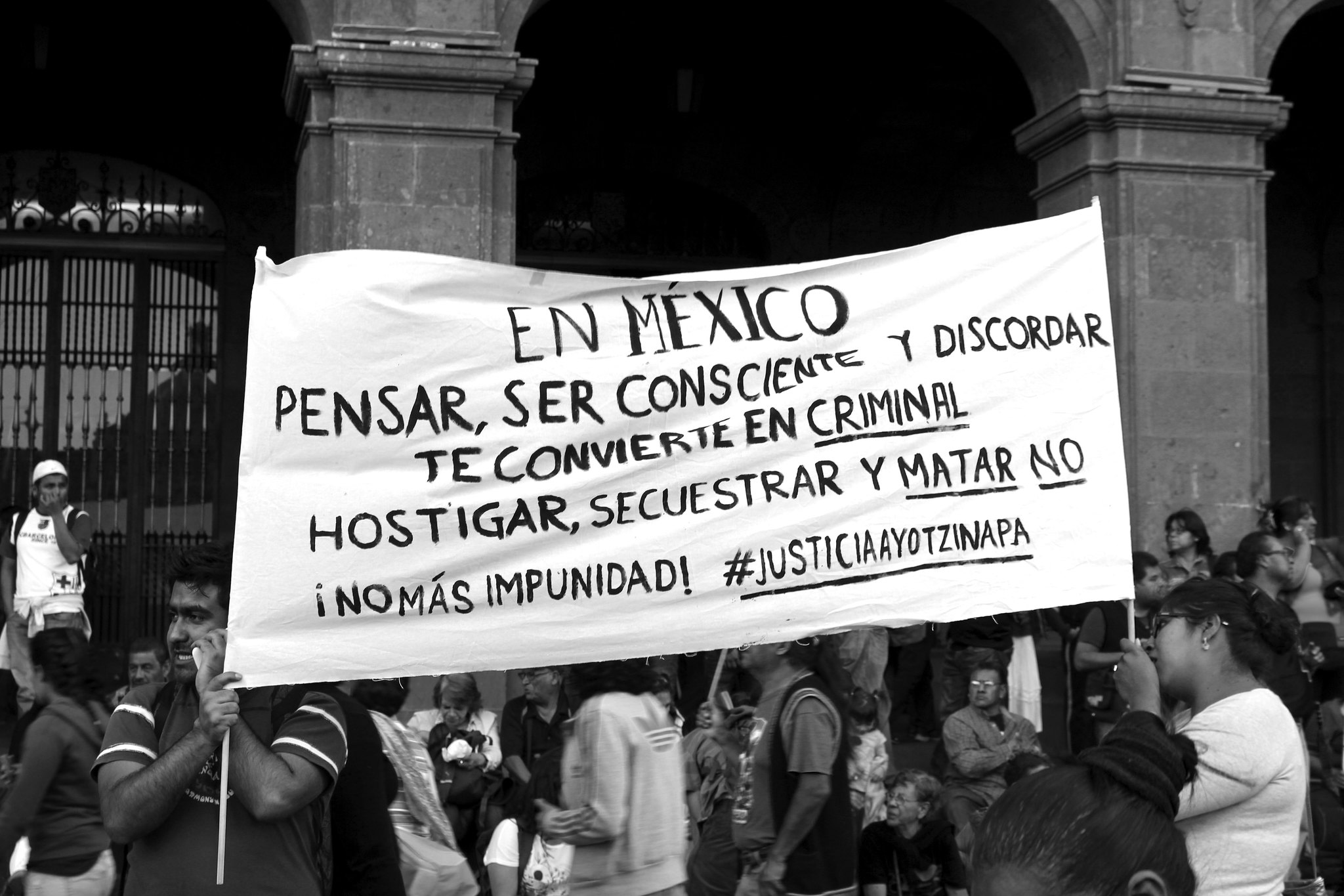 A Spanish-language banner protesting state repression at an Ayotzinapa rally.