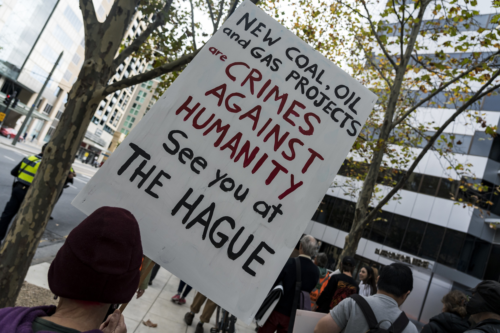 Sign at an APPEA protest in South Australia, 2023, which reads 'New coal, oil and gas projects are crimes against humanity. See you at the Hague.'