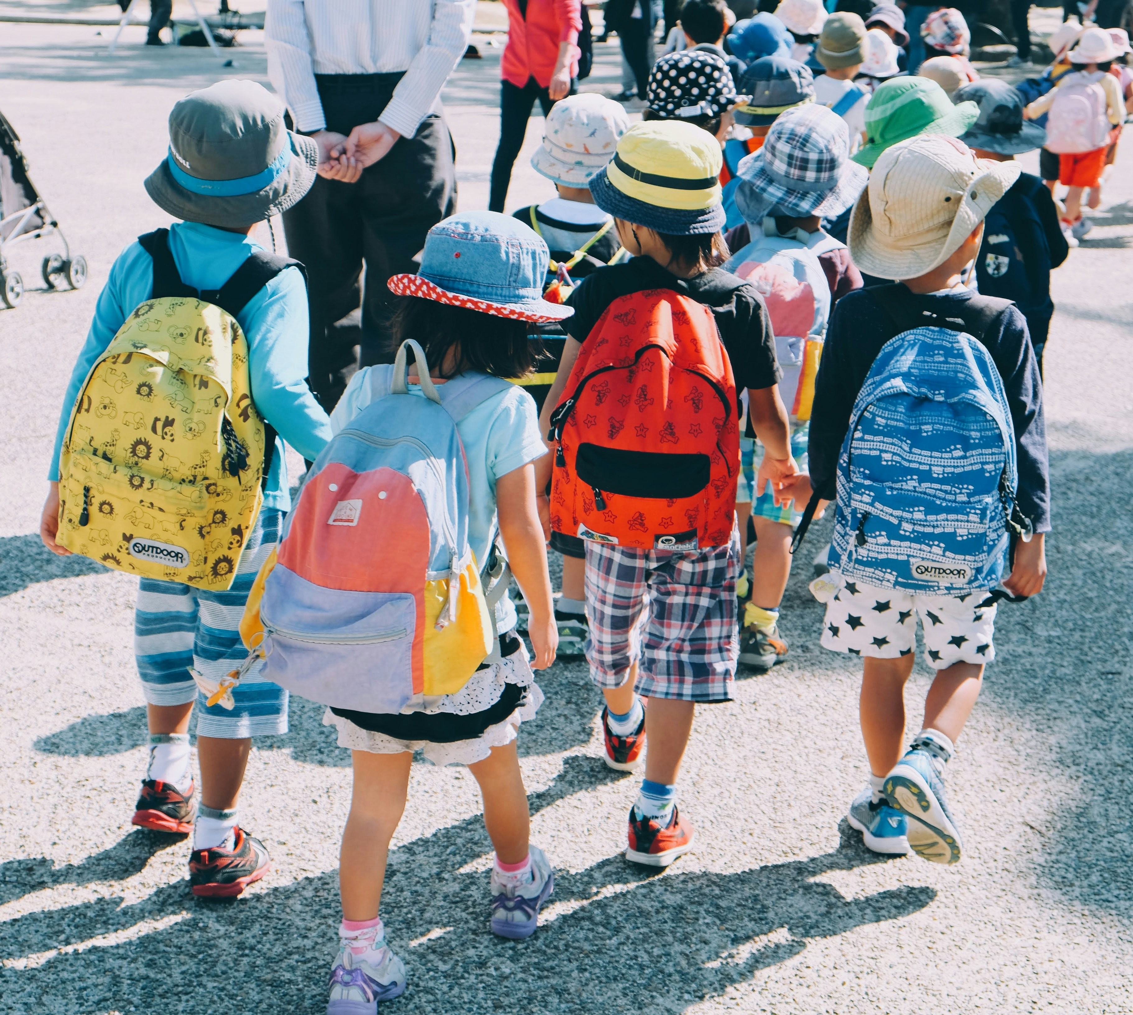 Group of school children wearing back packs and sun hats. 