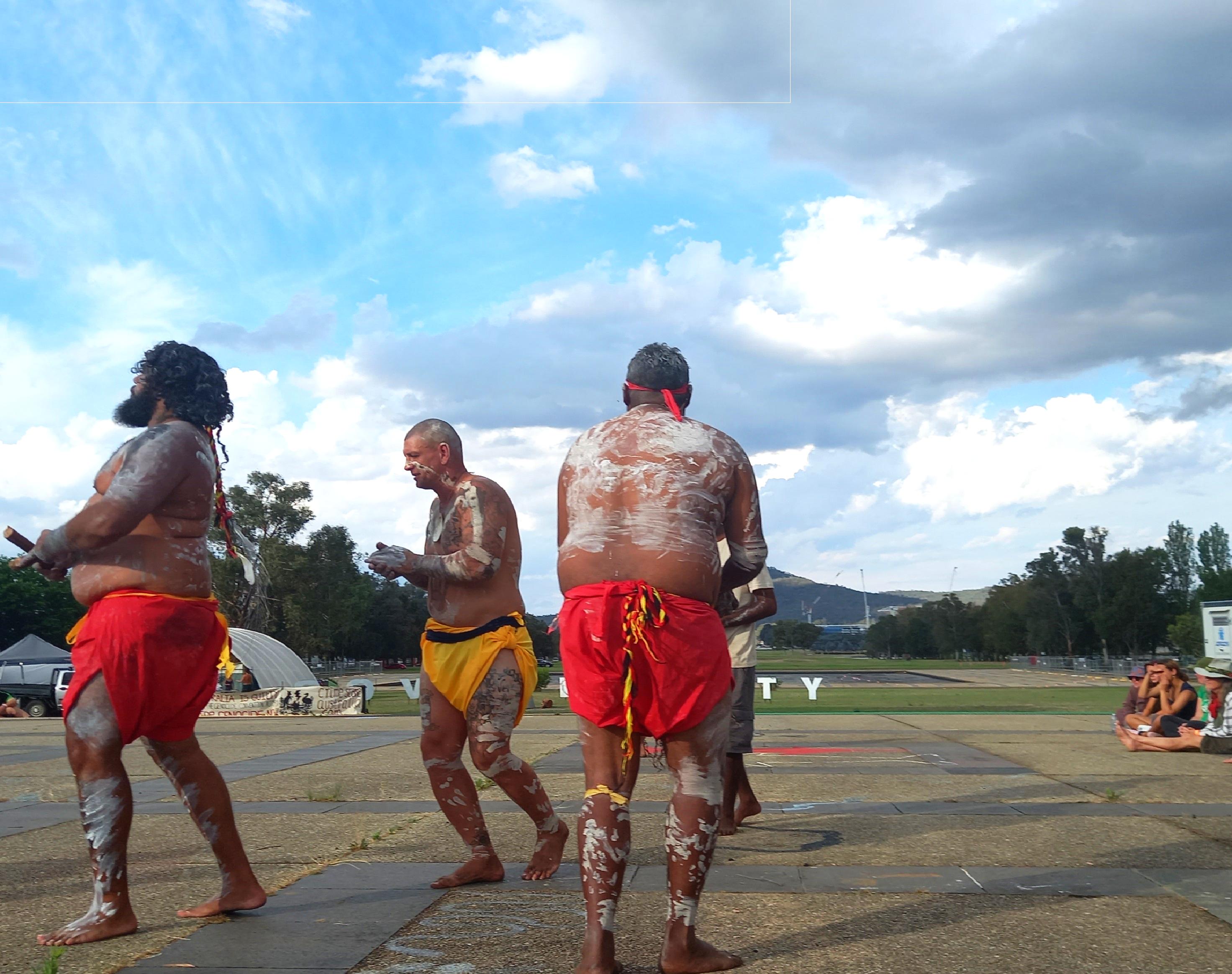 Three  painted up dancers dancing.