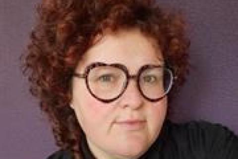 Dr Sophie Hindes brown curly hair large dark rimmed glasses