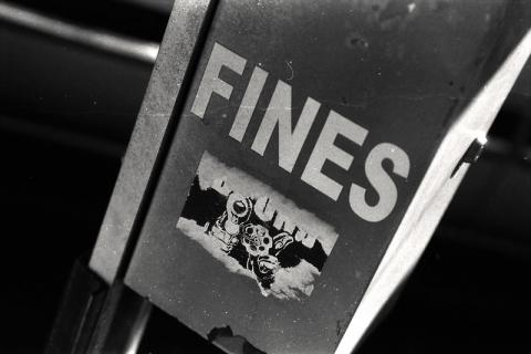 Sign with 'FINES' in black and white, with a sticker with a gun underneath