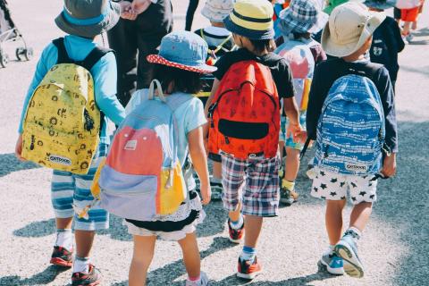 Group of school children wearing back packs and sun hats. 