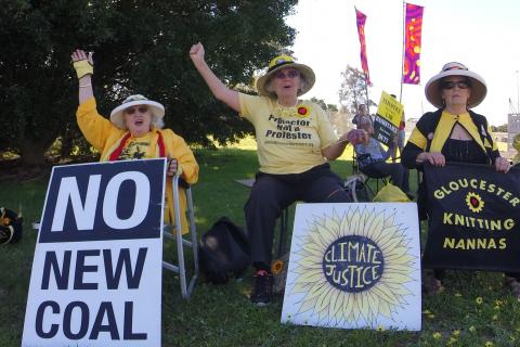 Three older women in yellow and black holding placards.