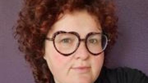 Dr Sophie Hindes brown curly hair large dark rimmed glasses