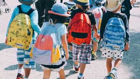 Group of school children wearing back packs and sun hats. 